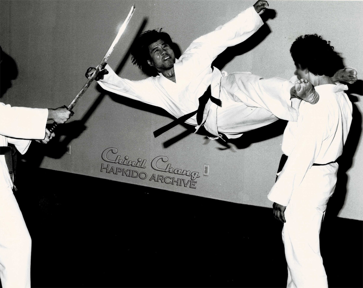 Chang demos a flying neck scissor tecnique with simultaneous sword defense